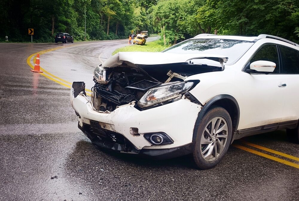 A white car was involved in an accident while navigating a bend in the road.